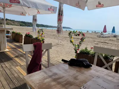 a wooden table and chairs on the beach at Bayview B32 - Burgas Beach Resort 2 in Burgas City