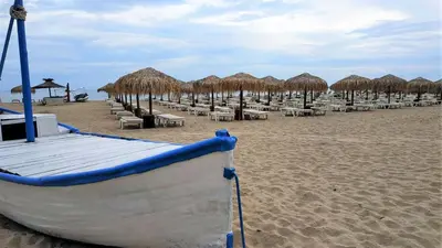 a row of chairs and straw umbrellas on a beach at Seaside Apartment with 2 Bedrooms for up to 5 Guests in Sunny Beach