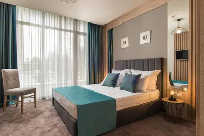 a bedroom with a bed and a chair and a window at Green Luxury Apartments in Burgas City