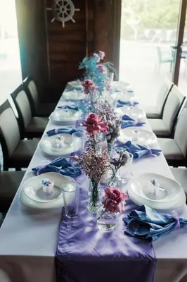a long table with plates and vases with flowers on it at Family Hotel Lalov Egrek in Lozenets