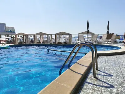 a swimming pool with chairs and blue water at Beachfront Apartments by Marty's in Sunny Beach