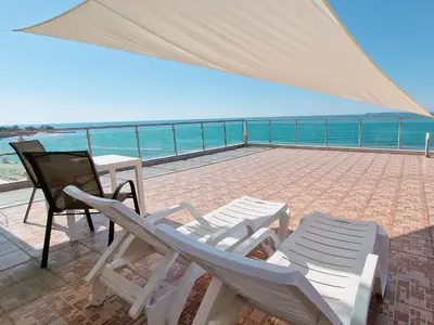 a patio with chairs and a table and the ocean at Beachfront Apartments by Marty's in Sunny Beach