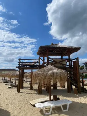 a row of wooden umbrellas and chairs on a beach at Manastira-2 (A-3) in Sveti Vlas