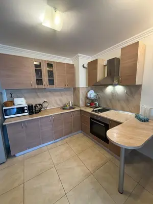 a large kitchen with wooden cabinets and a table at Manastira-2 (A-3) in Sveti Vlas
