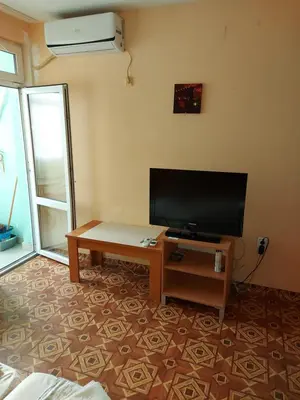 a living room with a flat screen tv and a table at Studio and 1bedroom apartment Burgas - Economy in Burgas City