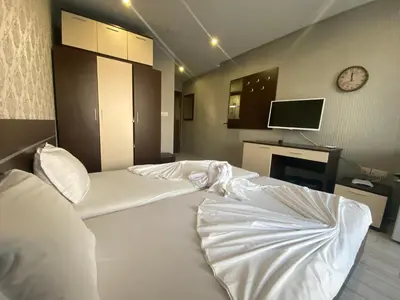 a bedroom with a large white bed with a clock on the wall at PARADISO B 209 Private Sea View Studio NESSEBAR in Nesebar