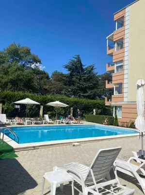 a swimming pool with chairs and umbrellas next to a building at Pomorie residence 2-bedroom apartment 300m to the beach in Pomorie