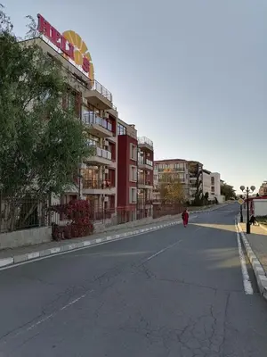 a person walking down a street next to a building at Helios 350m from the beach in Sveti Vlas
