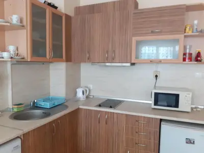 a kitchen with wooden cabinets and a sink and a microwave at Apartments Sea Sounds in Pomorie