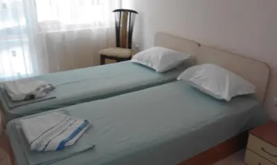 a bedroom with two twin beds with a chair and a window at Apartments Sea Sounds in Pomorie