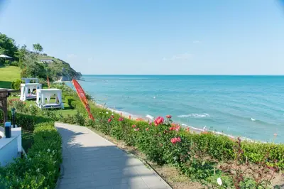 a walkway next to the ocean with flowers at White Cliffs, Byala in Byala