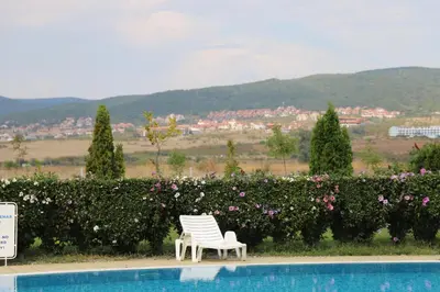 a pair of white chairs sitting next to a swimming pool at Holiday-Orchid Menada Apartments in Sunny Beach