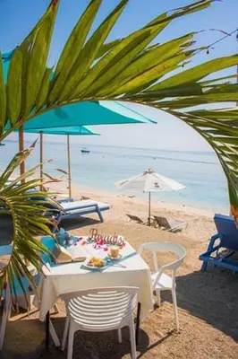 a table with chairs and umbrellas on a beach at Уютно и просторно студио in Ravda