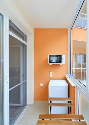a room with an orange wall with a refrigerator and a tv at Студио Патрисия in Pomorie
