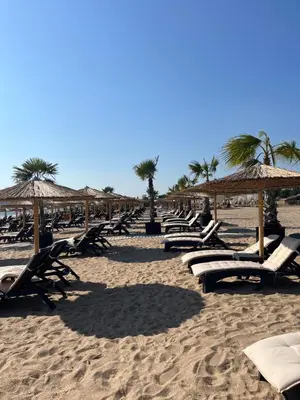 a row of lounge chairs and umbrellas on a beach at Къмпинг градина луксозен апартамент in Chernomorets