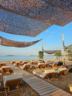 a beach with a bunch of chairs and a net at Къмпинг градина луксозен апартамент in Chernomorets