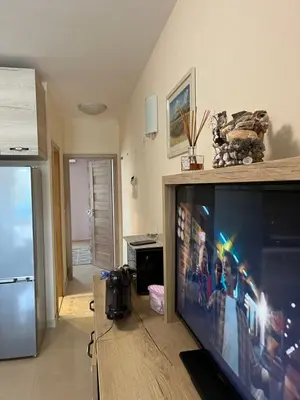 a living room with a flat screen tv and a kitchen at Къмпинг градина луксозен апартамент in Chernomorets