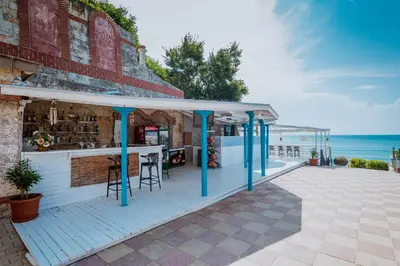 a bar on a deck with the ocean in the background at Tiva del Mar Beach Hotel in Sveti Vlas