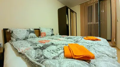 a bed with an orange blanket and pillows on it at Minimalistic 1BR flat with a Parking spot in Varna City