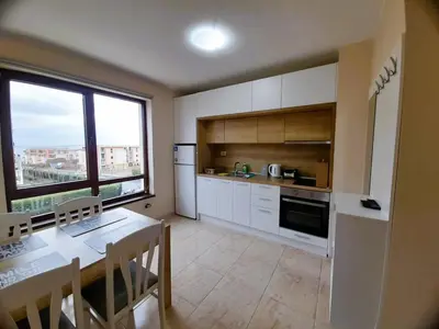 a kitchen with white cabinets and a table and a window at Sea Dreams Apartment in Sveti Vlas