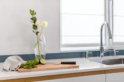 a kitchen counter with a cutting board with a vase of flowers at Апартамент Жасмин с частен гараж - Jasmin Apartment with private garage in Varna City