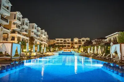 a large swimming pool in front of buildings at night at Green Life Beach Resort Apartment in Sozopol