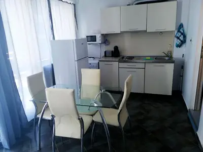 a small kitchen with a glass table and chairs at Private apartment with sea view in Blue Bay Pallace in Pomorie