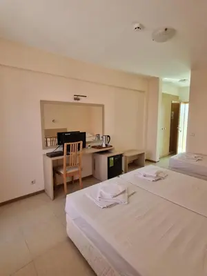 a hotel room with two beds and a desk and a table at Александра in Sveti Vlas
