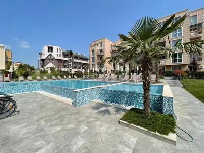 a swimming pool with a palm tree and buildings at Marea Garden apartments in Ravda