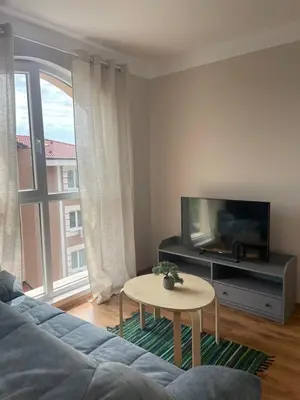 a living room with a couch and a tv and a table at Marea Garden apartments in Ravda