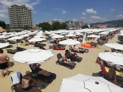 a bunch of people sitting on a beach with umbrellas at Dean's Cozy 2 Bed Apart at Sunny Beach resort in Sunny Beach