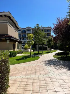 a brick walkway in a park with trees and buildings at Luxury Private Apartment near Green Life Resort in Sozopol