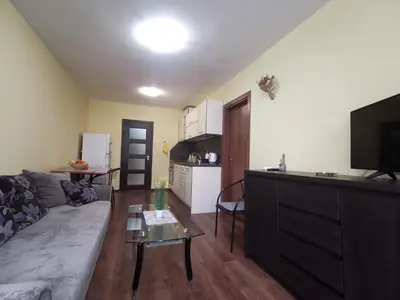 a living room with a couch and a tv and a kitchen at Двустаен апартамент в центъра на гр. Бургас in Burgas City