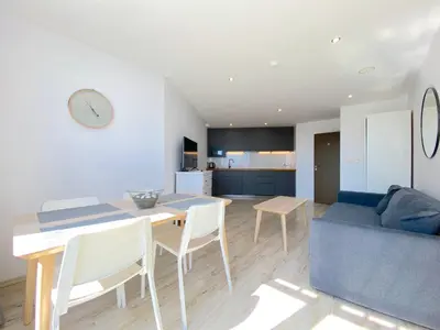 a kitchen and living room with a table and a blue couch at Paradiso Aparthotel - Private apartment -BSR-2 in Nesebar