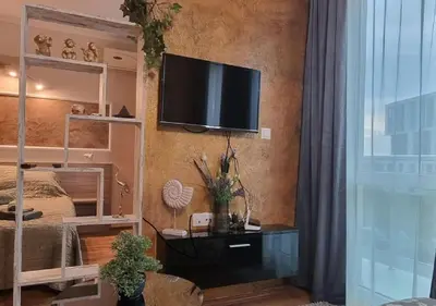 a bedroom with a bed and a television on a wall at Уютен апартамент близо до морето IGROEG in Burgas City