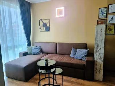 a living room with a brown couch and a table at Уютен апартамент близо до морето IGROEG in Burgas City
