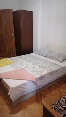 a bed in a room with a wooden cabinet at 27 юли 3 бюджет in Varna City