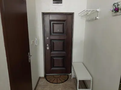 a brown door in a white room with a bench at Студио Прованс Лариса in Pomorie