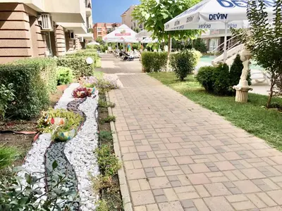 a walkway with rocks and flowers next to a building at Menada Casa del Sol Apartments in Sunny Beach