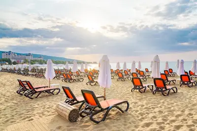 a group of chairs and umbrellas on a beach at Menada Casa del Sol Apartments in Sunny Beach