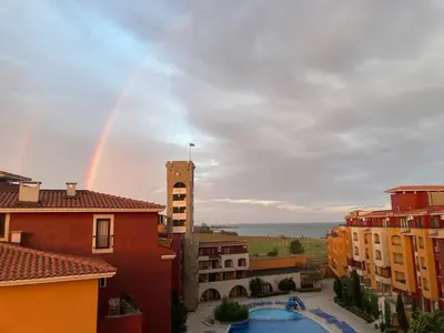 a rainbow in the sky over buildings and a pool at Art studio Marina Cape-private host in Ravda