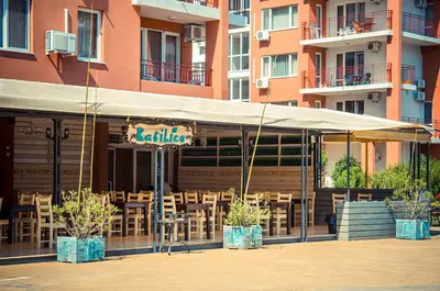 a restaurant with tables and chairs in front of a building at Apartament with See View in Sveti Vlas