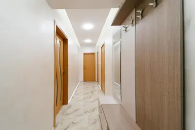 a corridor with white walls and wood floors and a hallway with doors at Апартамент за гости Веси in Burgas City