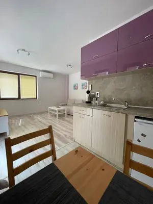 a kitchen with purple cabinets and a table and chairs at Къща за гости “Недев” in Tsarevo