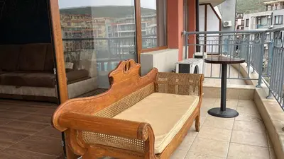 a wooden bed on a balcony with a table at Sun Wave Apartment Presige in Sveti Vlas