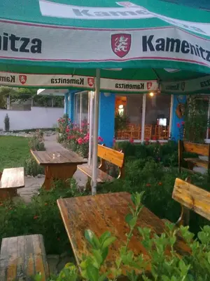 a group of benches and tables in front of a restaurant at Вила Синя Иглика in Kosharitsa