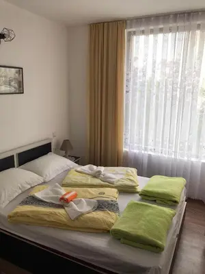 a bedroom with two beds with towels and a window at Апартамент Хармония in Sozopol