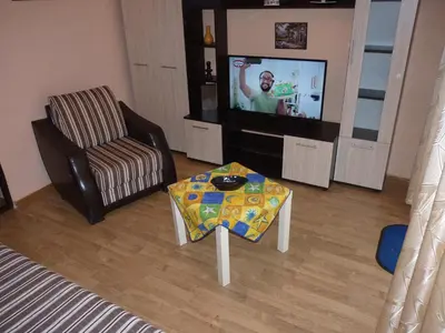 a living room with a tv and a table and a chair at Апартамент Хармония in Sozopol