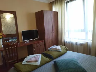 a bedroom with a bed and a desk and a television at Санта Марина in Varna City