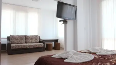 a living room with a couch and a bed and a tv at Къща за гости АЛЛА in Byala